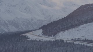 AK0001_1055 - 4K aerial stock footage Glenn Highway winding around snowy Talkeetna Mountain, Alaskan Wilderness