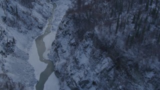 AK0001_1067 - 4K aerial stock footage river at bottom of snowy canyon, forest topped cliffs, Talkeetna Mountains, Alaska