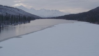 AK0001_1072 - 4K aerial stock footage flying over snow covered trees and lake, Matanuska River Valley, Alaska