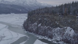 AK0001_1087 - 4K aerial stock footage following the Matanuska River toward snow covered, tree topped cliff, Alaska