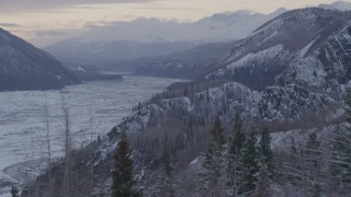 AK0001_1092 - 4K aerial stock footage flying over a snow covered, wooded cliff revealing Matanuska River Valley, Alaska