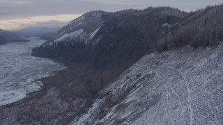 AK0001_1095 - 4K aerial stock footage ascending a snow covered cliff in the Matanuska River Valley, Alaska