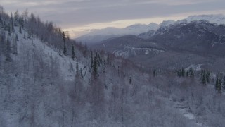 AK0001_1098 - 4K aerial stock footage flying over snow covered, wooded hills revealing Matanuska River Valley, Alaska