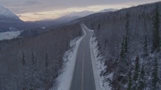 AK0001_1101 - 4K aerial stock footage following Glenn Highway and snow covered forest near Sutton at twilight, Alaska