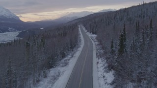 AK0001_1101 - 4K stock footage aerial video following Glenn Highway and snow covered forest near Sutton at twilight, Alaska