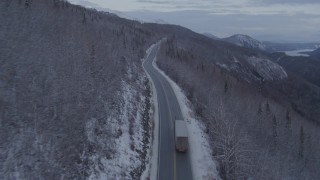 AK0001_1103 - 4K stock footage aerial video following a truck on Glenn Highway, near Sutton, in snow, at twilight, Alaska