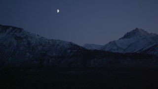 AK0001_1107 - 4K stock footage aerial video the moon over the snow covered Chugach Mountains at night, Alaska