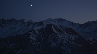 AK0001_1123 - 4K aerial stock footage the moon over the snow covered Chugach Mountains at night, Alaska