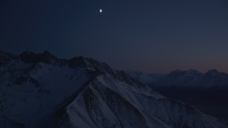 AK0001_1138 - 4K aerial stock footage the moon above the snow covered Chugach Mountains at night, Alaska