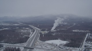 AK0001_1151 - 4K aerial stock footage following Glenn Highway toward power plant in snow, Anchorage, Alaska