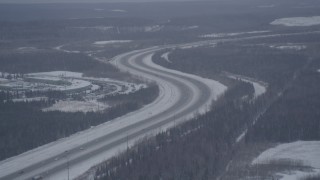 AK0001_1156 - 4K aerial stock footage Glenn Highway winding past snowy Bryant Army Heliport, Anchorage, Alaska