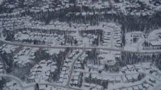 AK0001_1161 - 4K aerial stock footage flying over snow covered neighborhoods and trees in Eagle River, Alaska