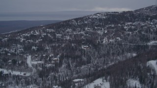 AK0001_1164 - 4K aerial stock footage flying over snow covered, wooded hills and homes in Eagle River, Alaska