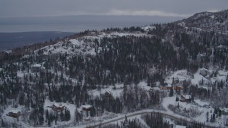 AK0001_1165 - 4K aerial stock footage flying over snow covered, wooded hills and homes in Eagle River, Alaska