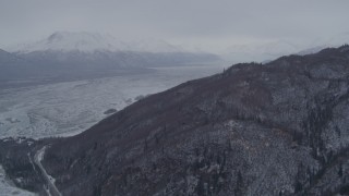 AK0001_1214 - 4K aerial stock footage fly away from snowy, wooded slopes, Knik River Valley, Chugach Mountains, Alaska
