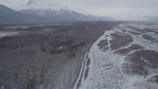 AK0001_1219 - 4K aerial stock footage flying along wooded, snow covered riverbank in Knik River Valley, Alaska