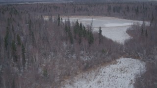 AK0001_1221 - 4K aerial stock footage flying over snow covered forest and lake in the Knik River Valley, Alaska