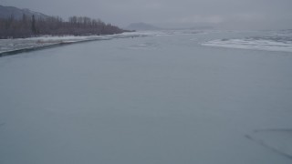 AK0001_1258 - 4K aerial stock footage flying over a river and sheets of ice in snow, Knik River Valley, Alaska