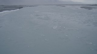 AK0001_1269 - 4K aerial stock footage flying low following an icy river, Knik River Valley, Alaska