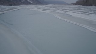 AK0001_1275 - 4K stock footage aerial video following an icy river over frozen banks, Butte, Alaska