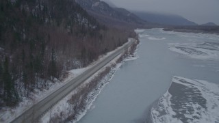 AK0001_1278 - 4K stock footage aerial video following Old Glenn Highway next to an icy river and snow, Butte, Alaska