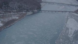 AK0001_1301 - 4K aerial stock footage fly over snowy shore, Glenn Highway, Highway 1 bridge, Knik River Valley, Alaska