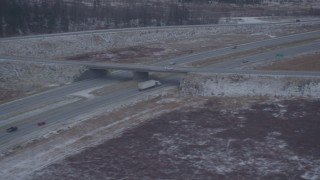 AK0001_1303 - 4K aerial stock footage light traffic on Glenn Highway by snow covered ground, Anchorage, Alaska