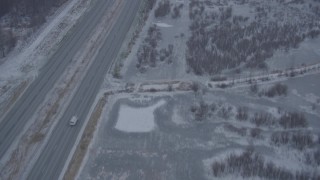 AK0001_1306 - 4K aerial stock footage following Glenn Highway through falling snow, Anchorage, Alaska