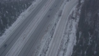 AK0001_1307 - 4K aerial stock footage following Glenn Highway through forest and falling snow, Anchorage, Alaska