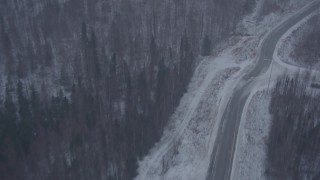 AK0001_1309 - 4K aerial stock footage flying over forest to Glenn Highway through falling snow, Eagle River, Alaska
