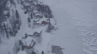 AK0001_1313 - 4K aerial stock footage flying away from snow covered neighborhoods and frozen lake, Eagle River, Alaska