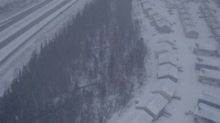 AK0001_1314 - 4K aerial stock footage flying over apartment buildings along Glenn Highway, falling snow, Eagle River, Alaska