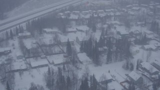 AK0001_1315 - 4K aerial stock footage flying over neighborhoods near Glenn Highway in falling snow, Eagle River, Alaska