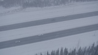 AK0001_1317 - 4K aerial stock footage light traffic on Glenn Highway in falling snow, Anchorage, Alaska