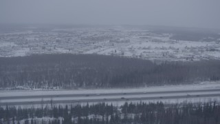 AK0001_1320 - 4K aerial stock footage tracking cars on Glenn Highway in falling snow, Fort Richardson, Anchorage, Alaska