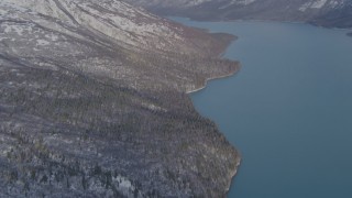 AK0001_1355 - 4K aerial stock footage approaching snow covered mountain slopes along shore of Eklutna Lake, Alaska