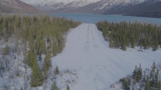 AK0001_1358 - 4K aerial stock footage descending toward strip of snowy ground by Eklutna Lake, Alaska