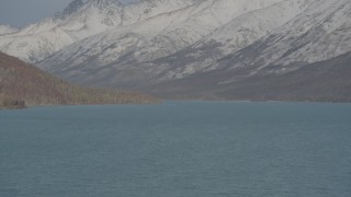 AK0001_1360 - 4K aerial stock footage surface of Eklutna Lake, snow covered, wooded hills, Chugach Mountains, Alaska