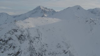 AK0001_1371 - 4K aerial stock footage flying over a snowy ridge toward Chugach Mountains, Alaska