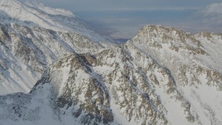 AK0001_1379 - 4K aerial stock footage flying toward rocky, snow covered mountain summit, Chugach Mountains, Alaska