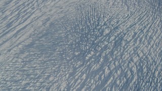 AK0001_1385 - 4K aerial stock footage tilt from the surface of the snow covered Knik Glacier, Alaska, reveal snowy mountains