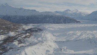 AK0001_1388 - 4K aerial stock footage flying along edge of snow covered Knik Glacier toward Chugach Mountains, Alaska
