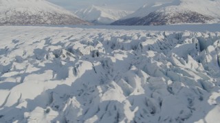 AK0001_1413 - 4K aerial stock footage flying low over surface of cracked, snow covered Knik Glacier, Alaska