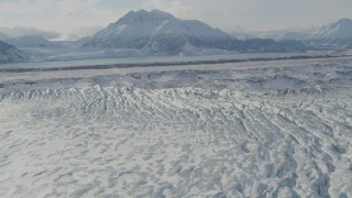AK0001_1430 - 4K aerial stock footage flying over snow covered Knik Glacier, Chugach Mountains in distance, Alaska