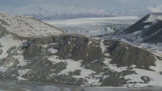 AK0001_1472 - 4K aerial stock footage flying over snowy ridge toward the glacier on Inner Lake George, Alaska