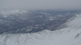 AK0001_1503 - 4K aerial stock footage the Eagle River Valley seen from snow covered Chugach Mountains, Alaska