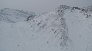 AK0001_1506 - 4K aerial stock footage flying over summit of snow covered mountain, Chugach Mountains, Alaska