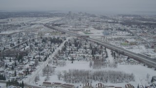 AK0001_1517 - 4K aerial stock footage fly over snowy neighborhoods, reveal Glenn Highway, Anchorage, Alaska