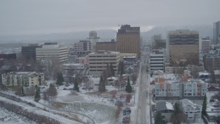 AK0001_1524 - 4K aerial stock footage flying over Cook Inlet into snowy Downtown Anchorage, West 5th Avenue, Alaska