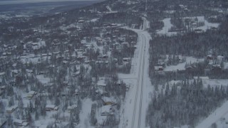 AK0001_1536 - 4K aerial stock footage following Eagle River Loop Road through snow covered neighborhoods, Alaska